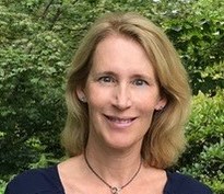 Lise Revers in front of some leaves. She has shoulder length dark blonde hair.