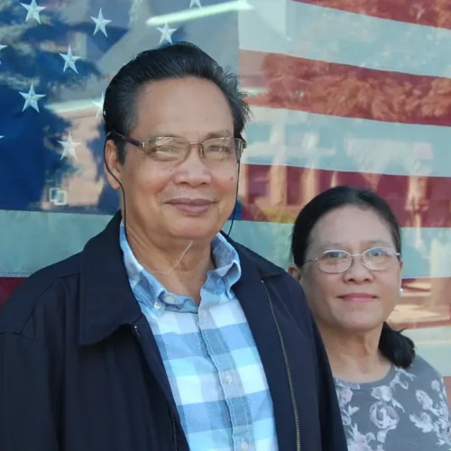 man and woman smiling in front of American flag