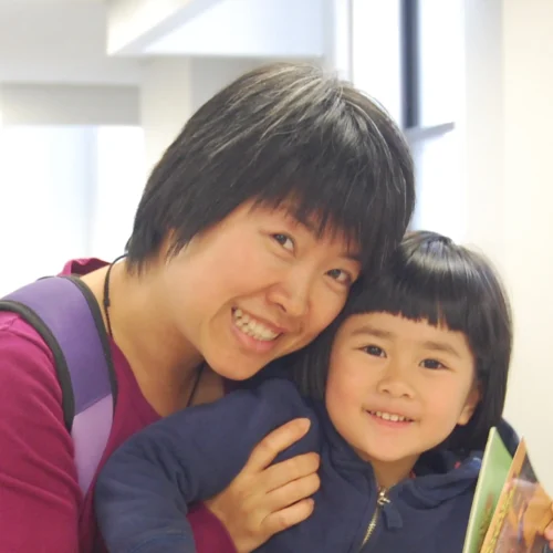 Mother smiling with her child at the camera. Both are wearing backpacks