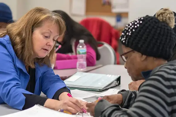 teacher showing senior woman information on paper