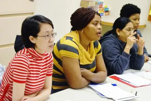 four women sitting at a long desk